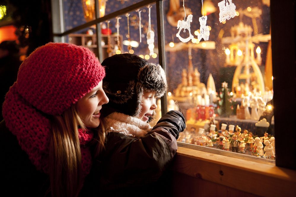 Mutter mit Kind vor festlich geschmücktem Schaufenster mit Weihnachtsfiguren und Schmuck – stimmungsvolles Adventserlebnis für Urlaubsgäste unserer Ferienwohnungen in Bad Berka.